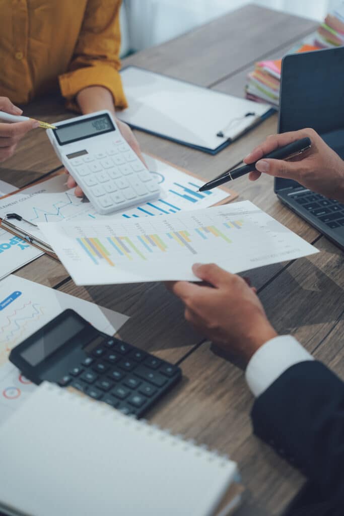 Analyse financière de données avec graphique et calculatrice Réunion d'affaires : mains analysant un graphique à barres et une ligne, avec une calculatrice affichant 4005.